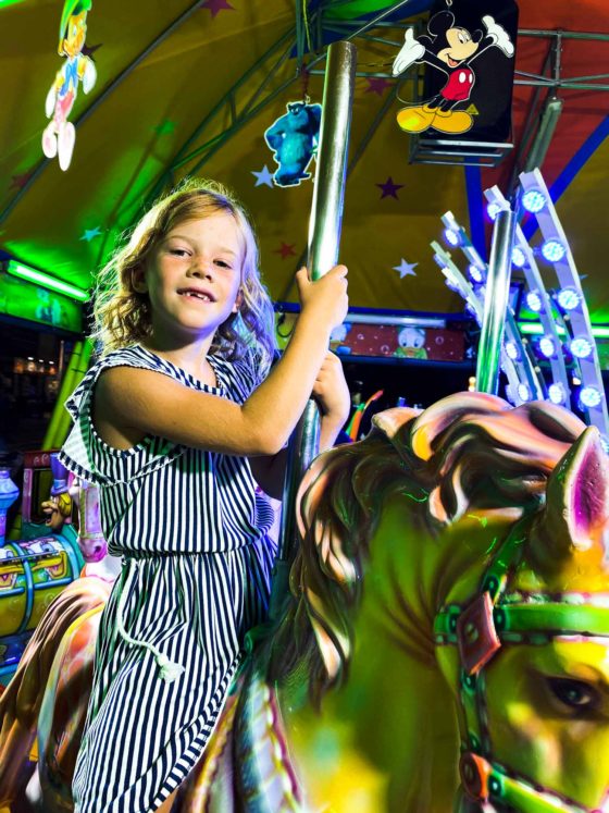 Girl riding a horse on a fairground carousel ride