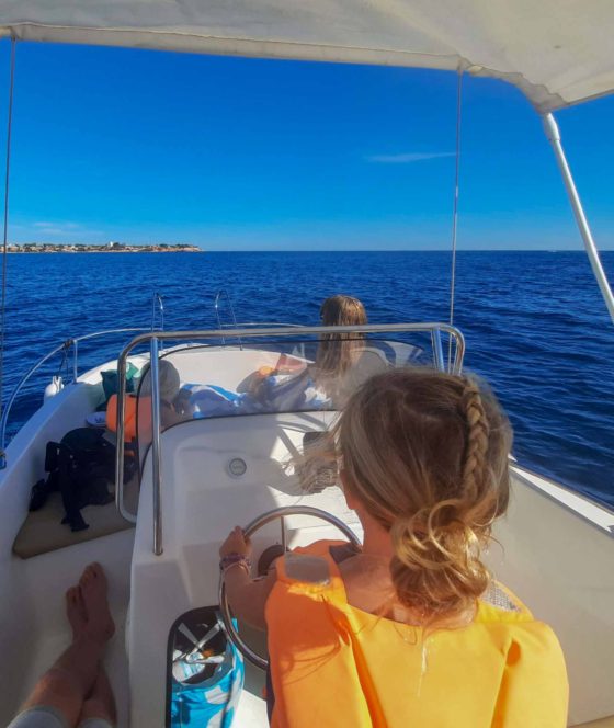 Young girl steering a small motor boat out at sea