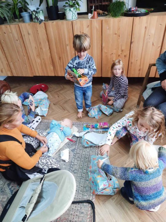 Group of small children sat on the floor opening presents