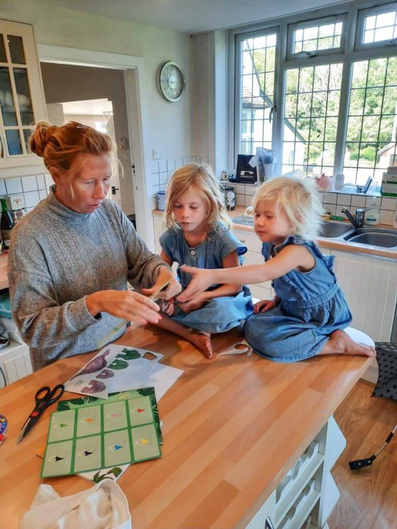 Mother with 2 small girls in a kitchen while cutting out cards for a craft activity
