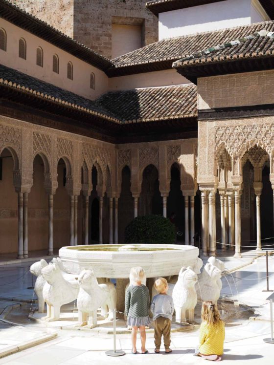 3 small children in front of a decorative Moorish-design water feature