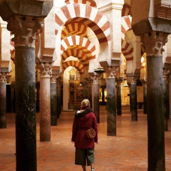 Lady walking through the inside of a cathedral with decorative arches and pillars