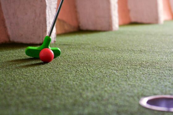 Close up of a putter, ball and hole, playing mini golf