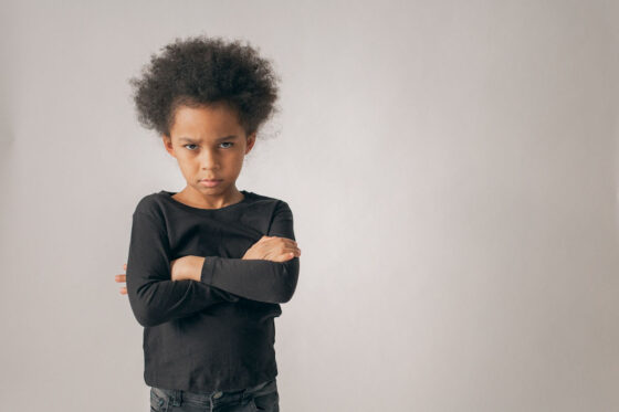 A child with arms crossed looking grumpy