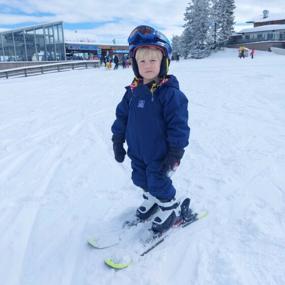Small boy stood on skis at a ski resort