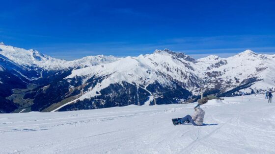 Lone snowboarder sat on a snowy ski slope