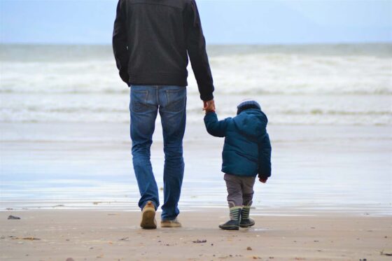 Father and child holding hands on a cold beach