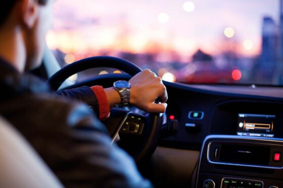 View from the back seat of a man wearing a watch driving a car