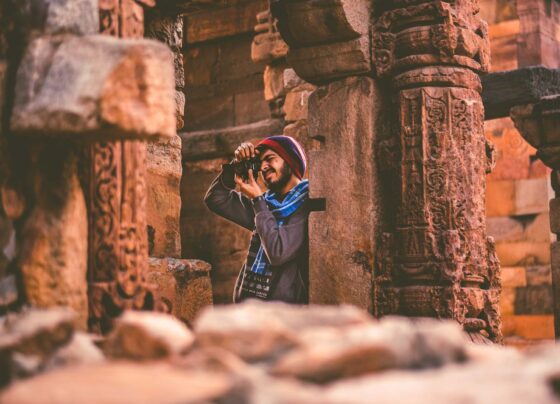 Man taking a photo inside an ancient temple with engraved stone columns