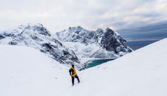 Mountaineer wearing a yellow jacket standing in a wild, snowy landscape