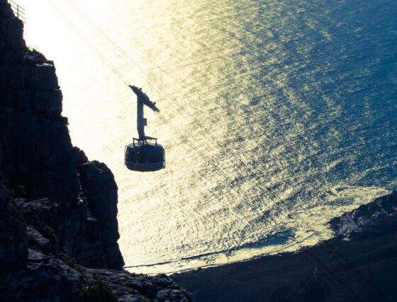 Cable car ascending a mountain with the sea behind