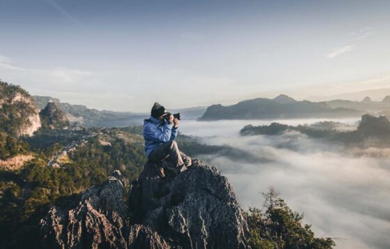 Man crouching in mountain wilderness taking a photo