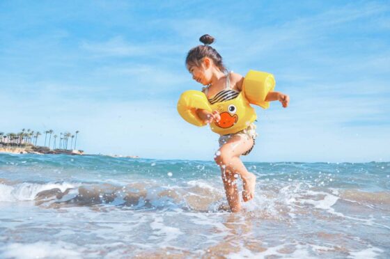 Small girl splashing in the sea with armbands on