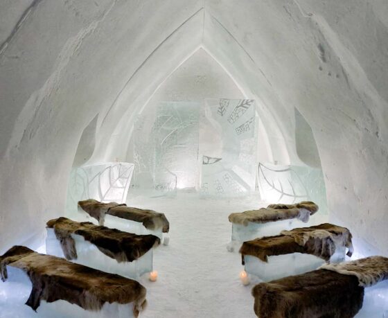 Inside a chapel made entirely of snow and ice with reindeer skins on bench seats