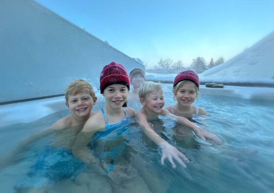 4 children in a hot tub with blue sky and snow around