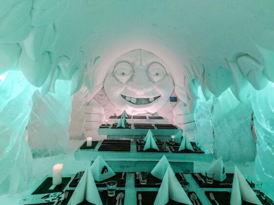 Inside a restaurant made out of snow and ice with ice carvings and sculptures and tables laid ready for dining
