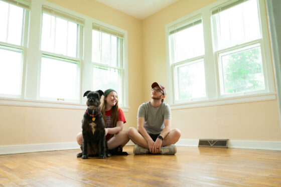 Couple with a dog sat on a wooden floor